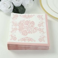 a pink and white napkin sitting on top of a table next to some white flowers