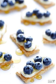 crackers with blueberries and cream on them are arranged in the shape of squares