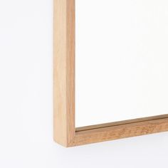 a wooden frame hanging on the wall with a white back ground and light wood trim