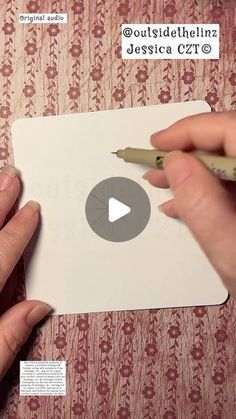 two hands holding a piece of paper with a video playing on it