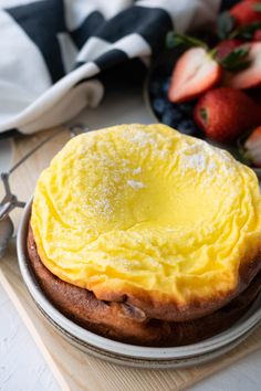 an omelet on a plate with strawberries and other fruit in the background