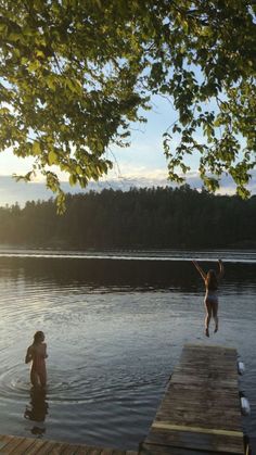 two people jumping into the water from a dock