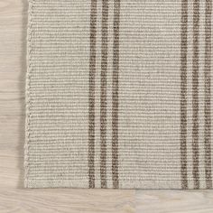 a beige and brown striped rug on top of a wooden floor