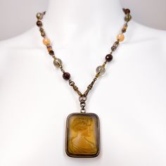 Extasia Cameo on Watch Chain - Reverse Carved Intaglio Rectangular Frosted Olive Glass Cameo - Multiple Semiprecious Faceted Gem Chain Gift  Vintage Cameo Necklace Brand: Extasia    Era: VINTAGE Description: - Earth and Champagne Tone Agates and Other Semiprecious Gems Make Up This Watch Chain Necklace Chain - Square Rectangle Cameo In Light Olive Frosted Glass - Unique Piece - Mid Century Masterpiece of a Necklace! - So Classic Condition - Very Good / No Scratches or Tarnishing  Chain Length:  20 INCHES / 51 CM I Have Had This Question Asked A Few Times; Yes, I accept Returns. I Always Want My Customer to Be Able To Trust Me and The Items I Sell. Please Contact Me As Soon As You Can with Any Concerns You May Have with The Piece of Jewelry Once You Receive It.  -  So Buy with Confidence; I Elegant Bronze Necklaces, Luxury Bronze Necklaces For Formal Occasions, Luxury Bronze Necklace For Formal Occasions, Vintage Amber Rectangular Jewelry, Elegant Bronze Cabochon Jewelry, Elegant Bronze Cabochon Necklace, Elegant Bronze Cameo Jewelry, Antique Rectangular Pendant Necklace For Formal Occasions, Elegant Antique Finish Pendant Necklaces