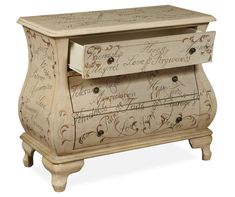 a white chest with writing on it and drawers in the bottom drawer is open to reveal an ornate design