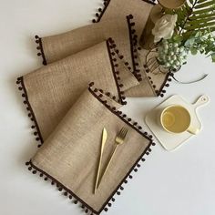 three placemats and two forks are sitting on a table next to a vase with flowers