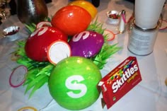 an arrangement of colorful balls and candy on a white table cloth with other items around it