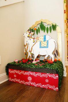 a cow statue sitting on top of a red and white box covered in greenery