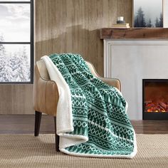 a chair with a blanket on it in front of a fireplace