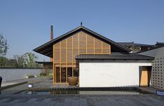 the house is made out of wood and has a large pool in front of it