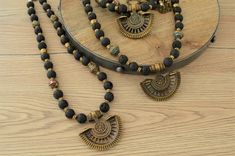 It's a unique black statement necklace with a brass plated with black patina locket pendant, black lava beads, brass balls and several bronze Nepali Brass beads. This rare locket pendant has a cabochon setting on one side and an engraved flower on the other and its engraved symbols are inspired by ancient Greek and Roman art. These beautiful antique bronze Nepali Brass beads have turquoise, lapis lazuli (blue colour), malachite (green colour) and coral inlay and its design is inspired by the ama