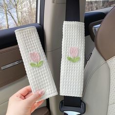 two white towels with pink flowers on them are held in the back seat of a car