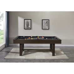 a pool table in a living room with two pictures on the wall and carpeted floor