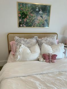 a bed with white sheets and pink pillows