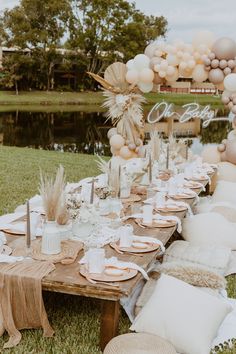 a table set up with balloons, plates and napkins for an outdoor dinner party