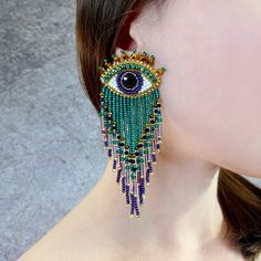 a close up of a woman's face wearing earrings with an evil eye on it