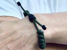 a close up of a person wearing a green bracelet with black beads on his wrist