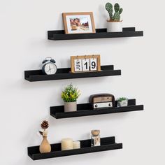 two black floating shelves with pictures and other items on them, one shelf has an alarm clock