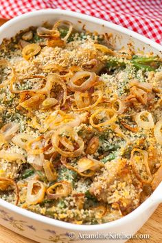 a casserole dish with broccoli, onions and cheese in it on a wooden cutting board