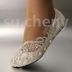 a woman's white wedding shoe with pearls and lace on the bottom, in front of a silver background