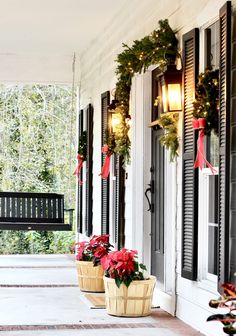 two planters filled with poinsettias sit on the front porch of a house