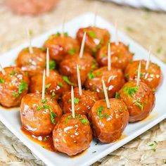 small meatballs with toothpicks on a white square plate and garnished with parsley