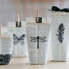 four paper cups with black and white designs on them, tied to clothes pins in the shape of butterflies