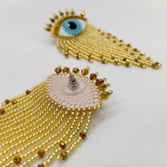 two pairs of gold earrings with blue eyes