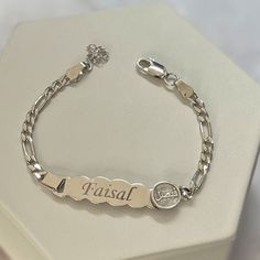 a silver bracelet with the word falsaf engraved on it, sitting in a white box