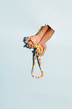 a person's hand holding a colorful beaded lanyard on a white background