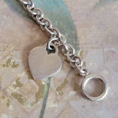 This is a vintage, sterling silver, link, bracelet with a toggle clasp and heart pendant/charm. This has tested positive for sterling silver. There is some wear/superficial scratches to the heart, as you can see in the images. All sales are final. This measures 7.25 inches in length x 8 mm in width. The heart is 1 and 1/8 inches in length including the bale. If you have a wish list or are looking for something specific, please ask. I may have exactly what you are looking for. As always please convo me with any questions or concerns regarding this item or with any international shipping questions. Unfortunately I do not accept returns or grant refunds. All shipping fees include handling fees. If you would like to combine shipping costs for more than one item, I would be happy to do so if yo Classic Sterling Silver Heart Charm Bracelet, Heart-shaped Charm Bracelet With Toggle Clasp As Gift, Heart Charm Bracelet With Toggle Clasp For Gift, Classic Sterling Silver Charm Bracelet With Heart, Sterling Silver Heart Bracelet With Charms, Vintage Sterling Silver Everyday Bracelets, Vintage Sterling Silver Everyday Bracelet, Vintage Sterling Silver Bracelets For Everyday, Silver Heart-shaped Bracelet With Toggle Clasp