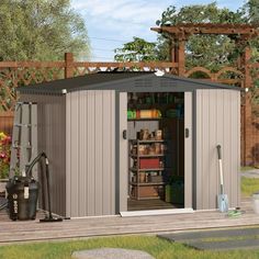 an outdoor storage shed with its doors open and tools on the ground next to it