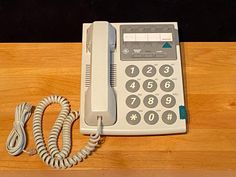 an old style telephone sitting on top of a wooden table next to a charger