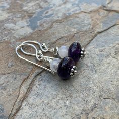 Deep, dark amethyst and rainbow moonstone are beautifully paired in these artisan earrings. Accented with sterling silver. The ear wires and headpins are also sterling silver. Total length: 1.25 inch Amethyst: 10 x 6mm Moonstone: 6 x 3mm Your jewelry will arrive in a cotton lined kraft box within a padded postal envelope. I use USPS first class mail. This usually takes 3 to 5 days to ship. International orders outside of the U.S. will take 8 to 15 days to ship. To see more from East Village Jewe Dark Amethyst, Labradorite Bracelet, Bride And Groom Gifts, Artisan Earrings, Homemade Jewelry, East Village, Head Pins, Amethyst Earrings, Silver Accents