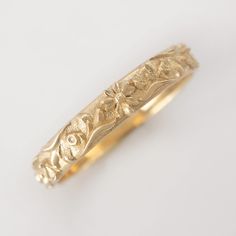 a gold wedding band that has been carved into the shape of an ornate flower and leaves