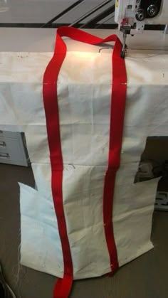 a white bag sitting on top of a table with a red ribbon tied around it