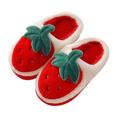 a child's hand is holding up a pair of strawberry slippers