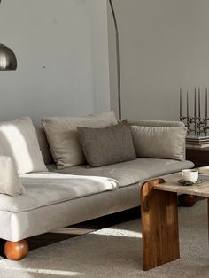 a living room filled with furniture and a lamp on top of a wooden table in front of a white wall