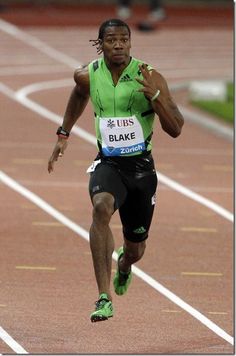 a man running on a track in a green shirt