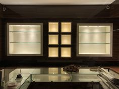 an empty glass display case in a dark room with wood paneling and white walls