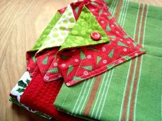 several folded cloths sitting on top of a wooden table with green and red designs