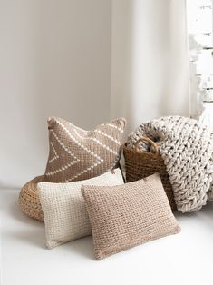 four pillows and a basket on a white surface