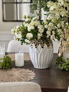 a vase filled with white flowers sitting on top of a wooden table next to candles