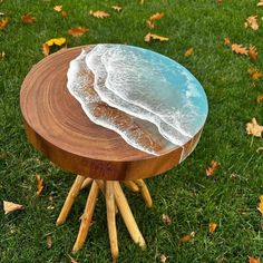 a small wooden table with an ocean wave on it's top in the grass