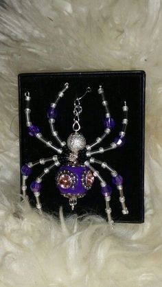 a purple and silver spider brooch sitting on top of a white fur