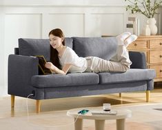 a woman laying on a couch reading a book