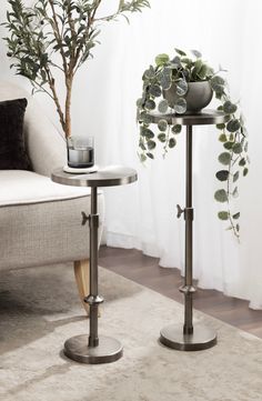 two tables with plants on them in front of a couch