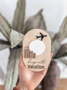 a person holding up a wooden plaque with an airplane flying over it that says, keep in all vacation