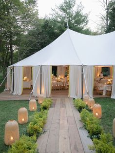 a large white tent set up in the middle of a field with candles lit inside