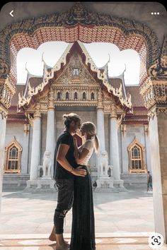 a man and woman are standing in front of a building with ornate designs on it